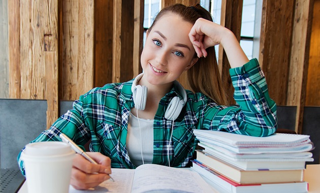 Young girl sitting at desk with notebook, books, and coffee