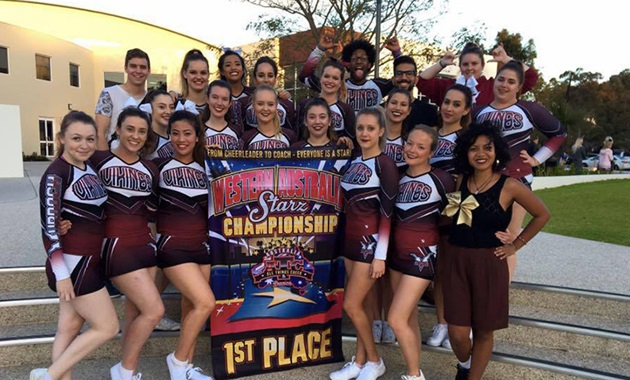 18 members of the Murdoch University Cheerleading Team in uniform, smiling and posing with a 1st place banner