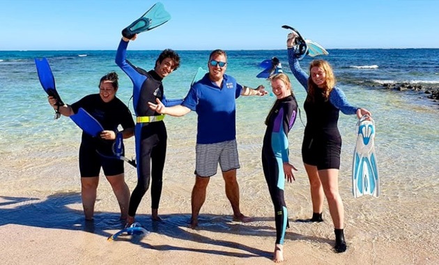 Students with academic in dive gear on the beach