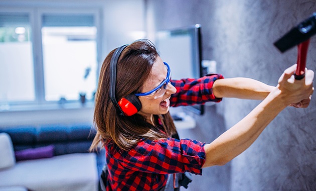 Woman smashing wall with tool