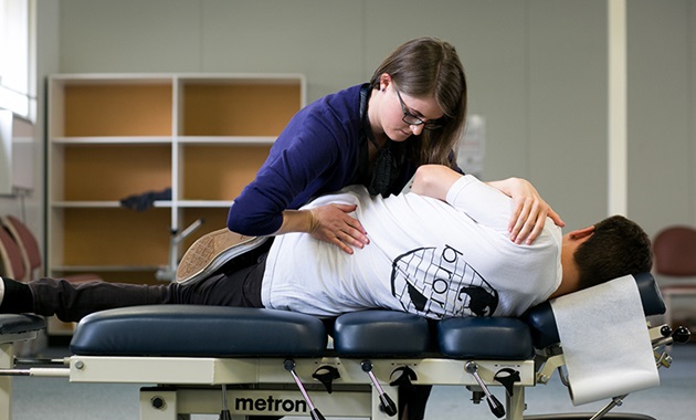 Female chiropractor performing adjustment on male patient