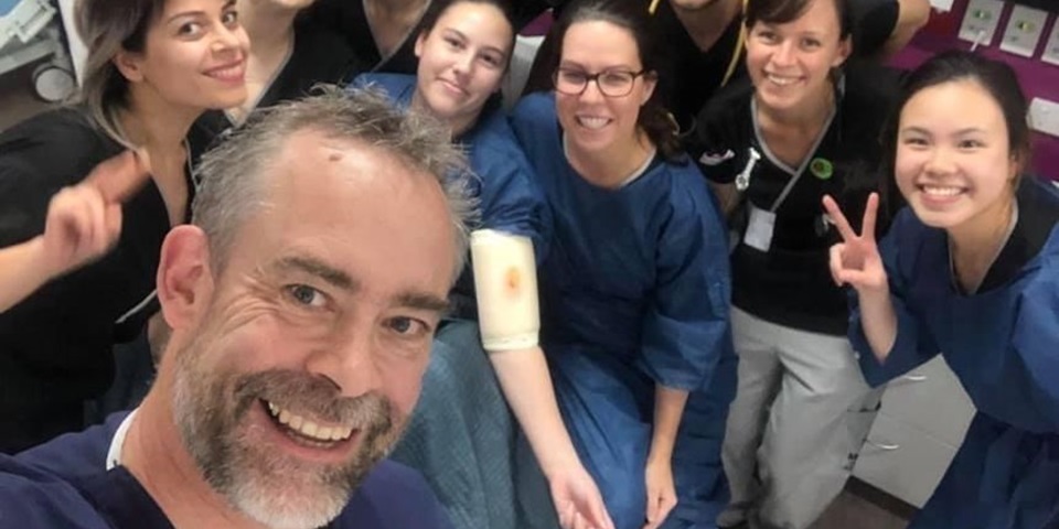 A group of Murdoch nursing students in scrubs smile to camera with their lecturer