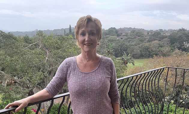 Cynthia stands on her balcony overlooking the South African jungle