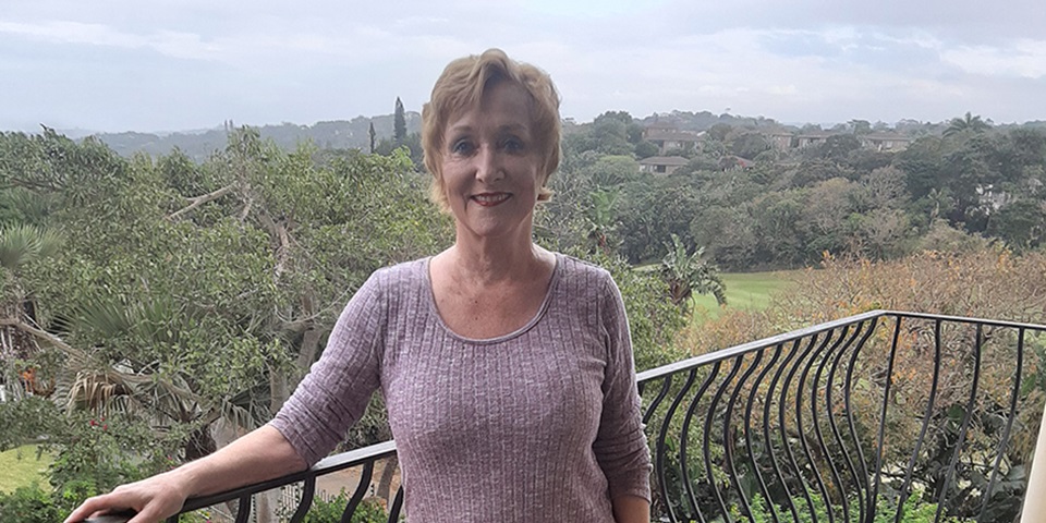 Cynthia stands on her balcony overlooking the South African jungle