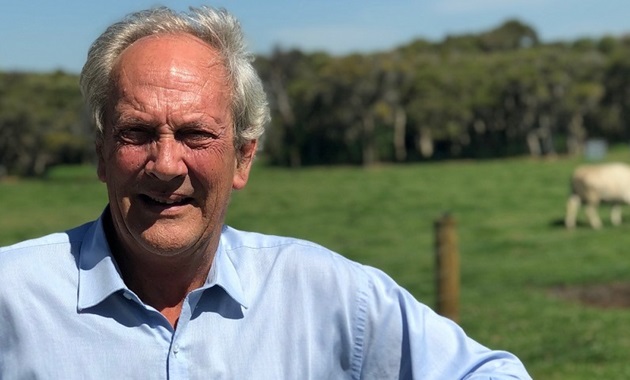 Professor David Pethick standing by a farm gate with cow in the background