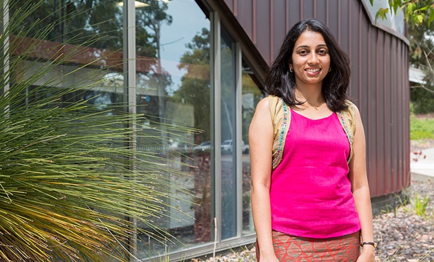 Student Deepa Machaiah posing and smiling outside building and grass tree at Murdoch