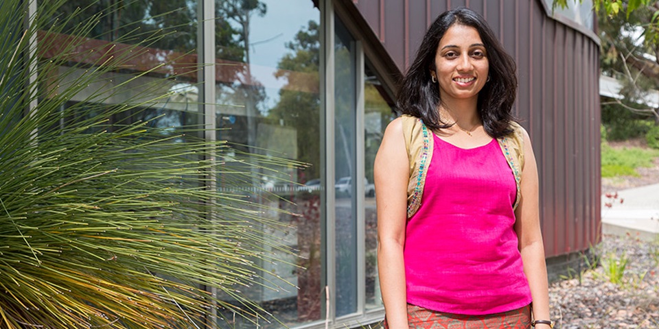 Student Deepa Machaiah posing and smiling outside building and grass tree at Murdoch