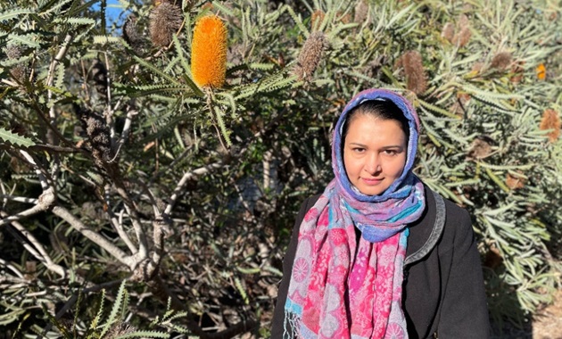 Dr Umera Imtinan standing among orange banksias