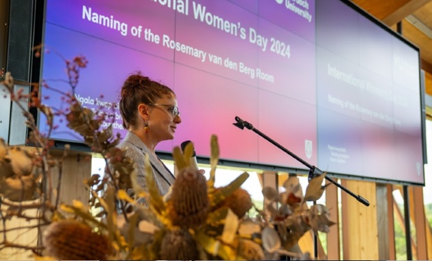 Dr Rebecca Bennett presenting at a lectern on International Womens Day