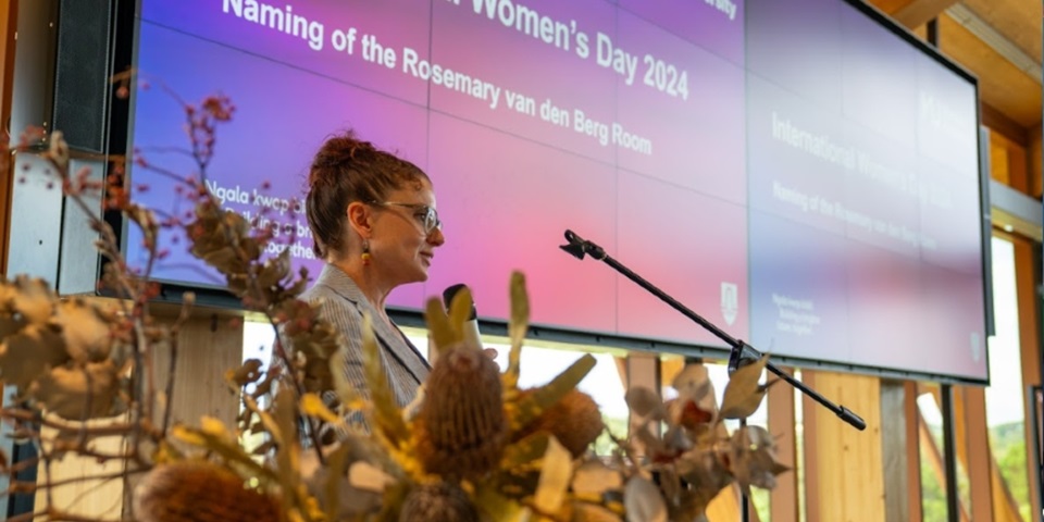 Dr Rebecca Bennett presenting at a lectern on International Womens Day