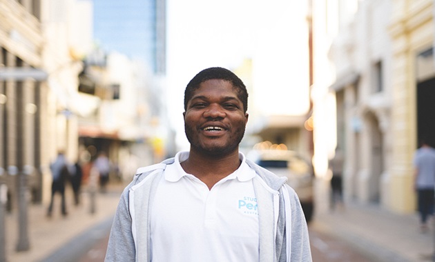 International student Emmanuel Dei standing and smiling on King Street, Perth