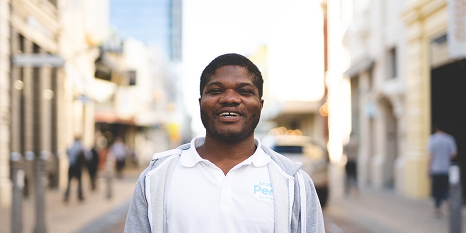 International student Emmanuel Dei standing and smiling on King Street, Perth