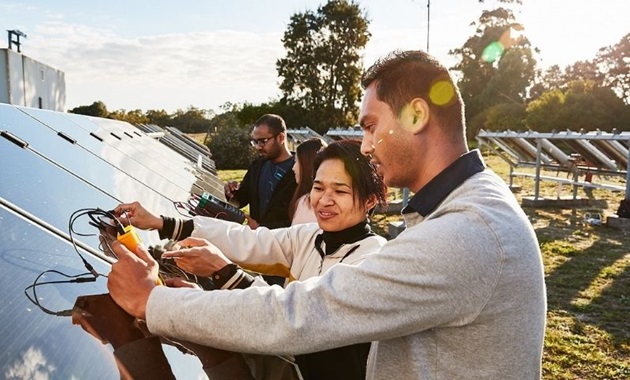 Students examine a solar power panel outside