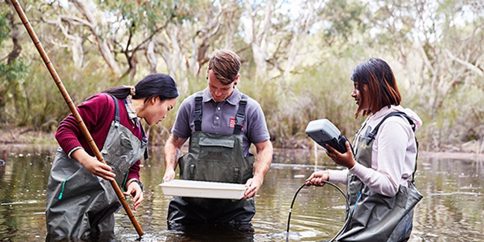 Three students experimenting in a lake.