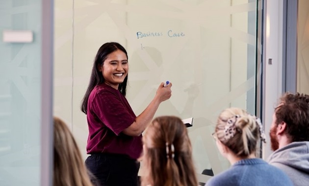 Student writes on board with classmates