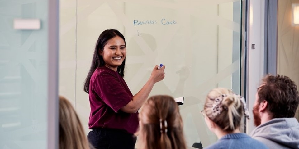 Student writes on board with classmates