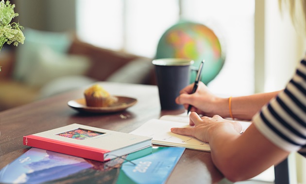 Feature image of woman sitting at a desk writing in a notebook