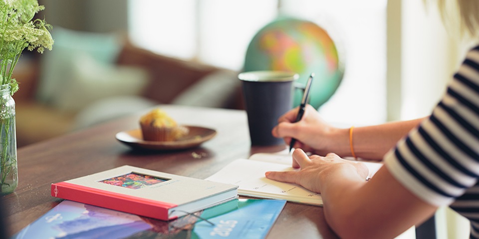 Feature image of woman sitting at a desk writing in a notebook