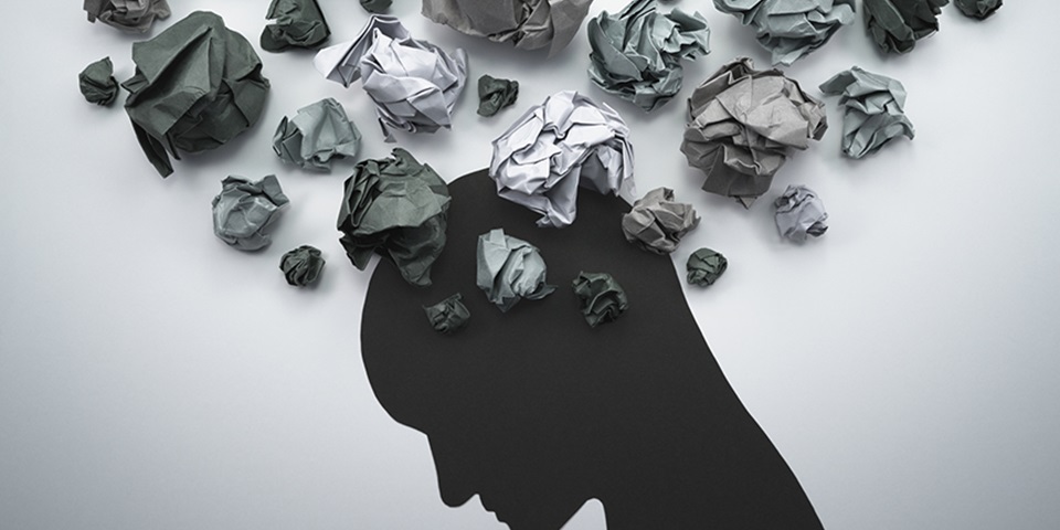 Silhouette of head looking down with scrunched up paper resembling thoughts