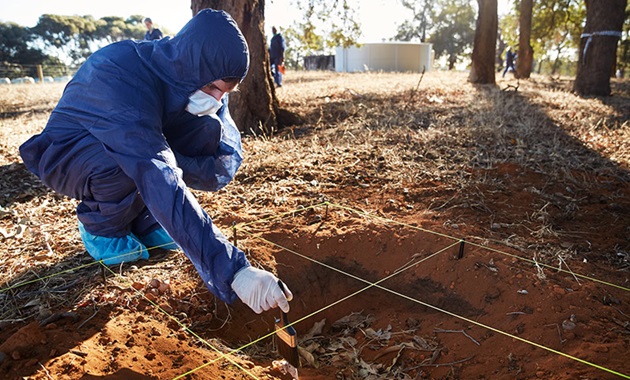 forensic student dusting evidence in sand