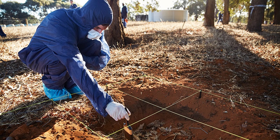 forensic student dusting evidence in sand