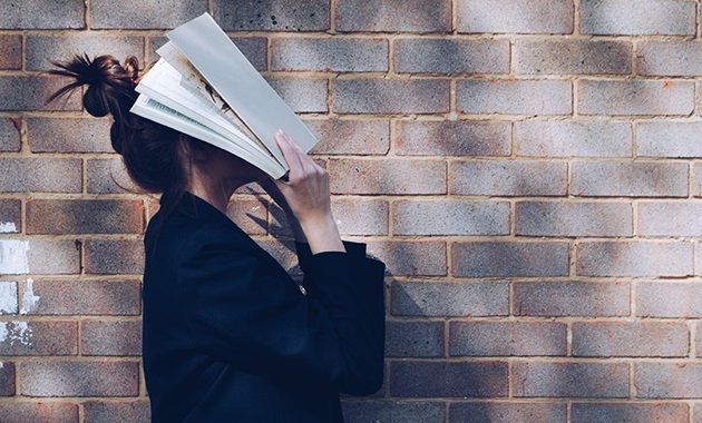 Girl holding book to face