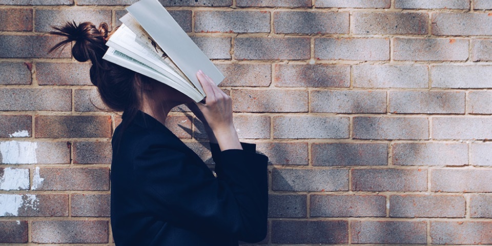 Girl holding book to face