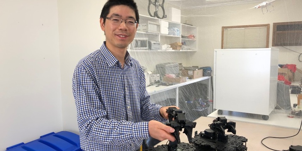 Dr Wai Hang in a lab with robots