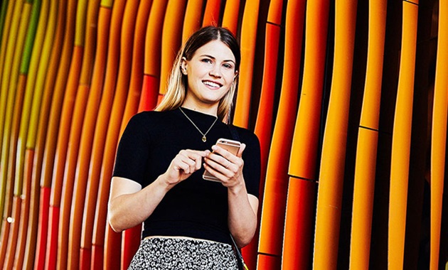 Student using mobile phone and smiling at camera