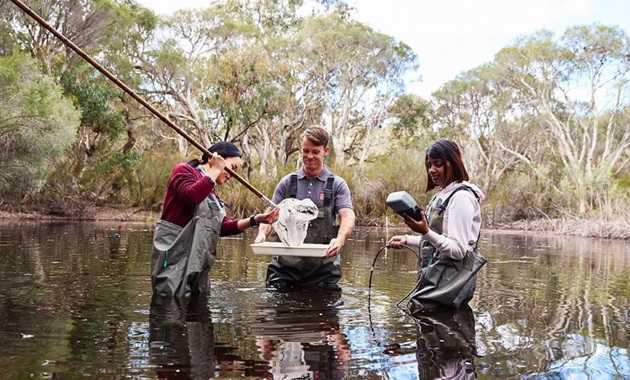 Murdoch students standing in lake testing water