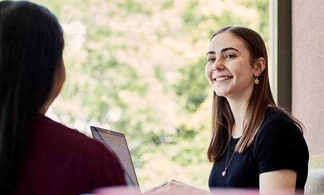 Students having a conversation in front of a laptop