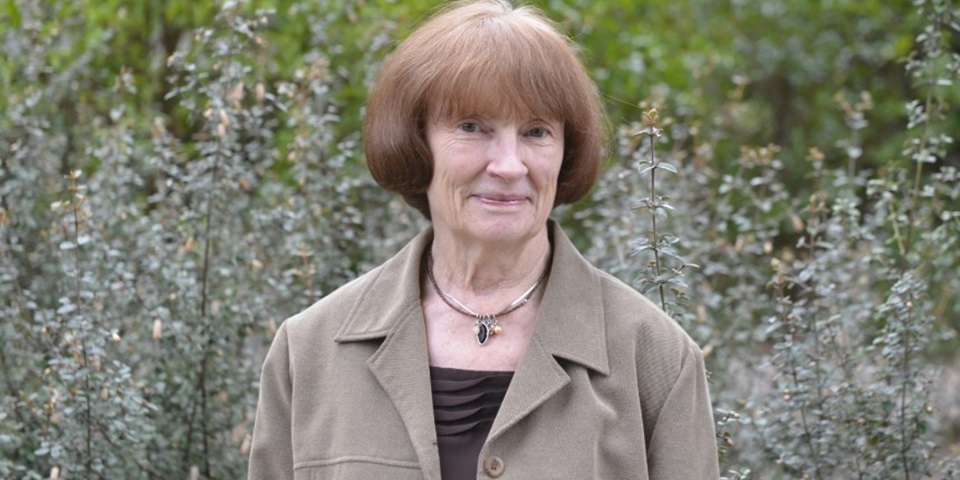 Janet Bornman smiling next to bushes