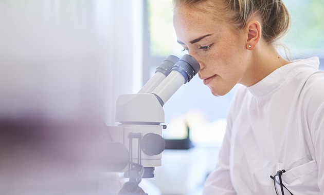 Lab Assistant looking through a microscope