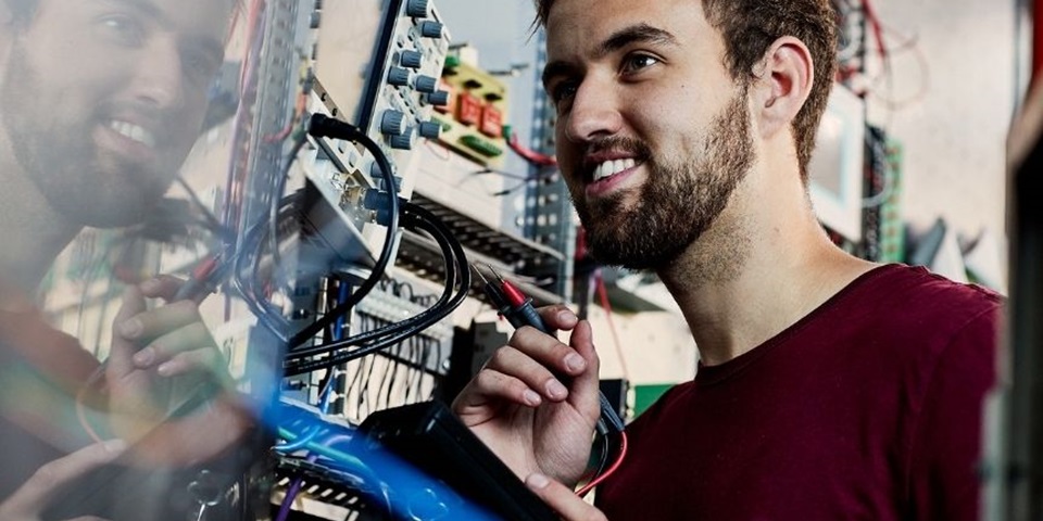 Student smiles and inspects electrical switchboard