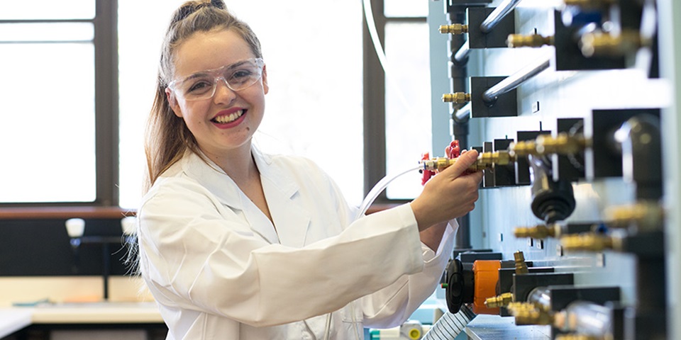 Female student smiling next to equipment.