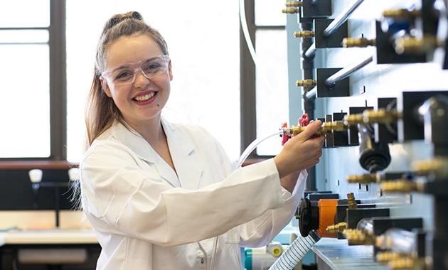 Female student smiling next to equipment.