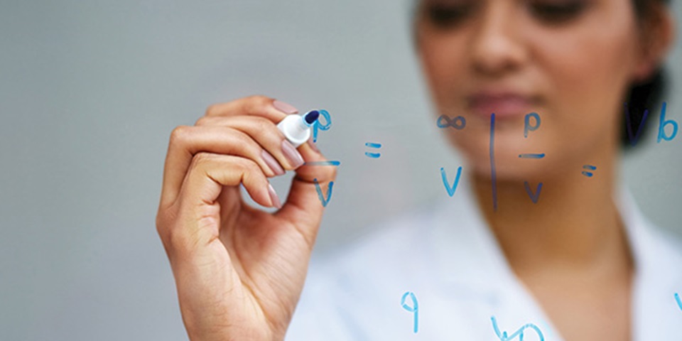 Woman writes equations on glass.