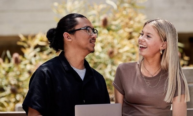 Two teens sitting together by a laptop