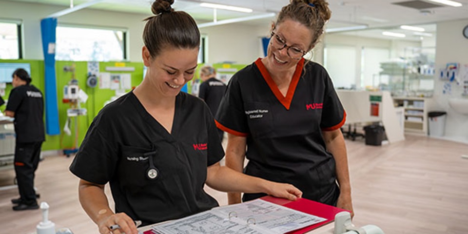 Female student looks over file with female tutor in the SimLab.