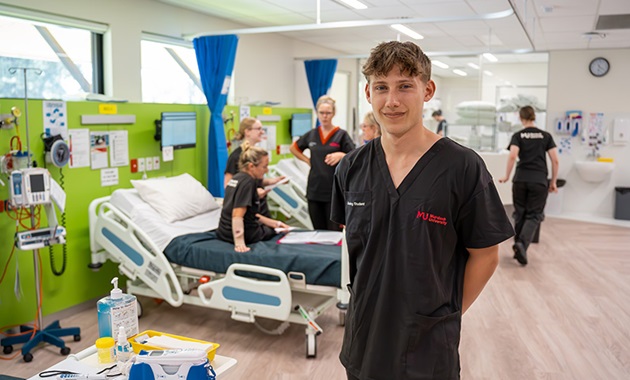 Male student stands in front of class in the SimLab.