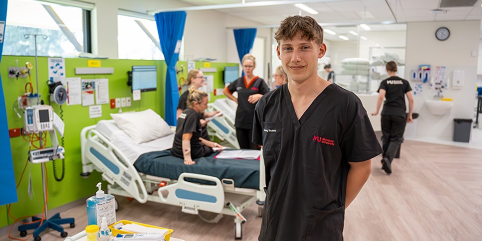 Male student stands in front of class in the SimLab.