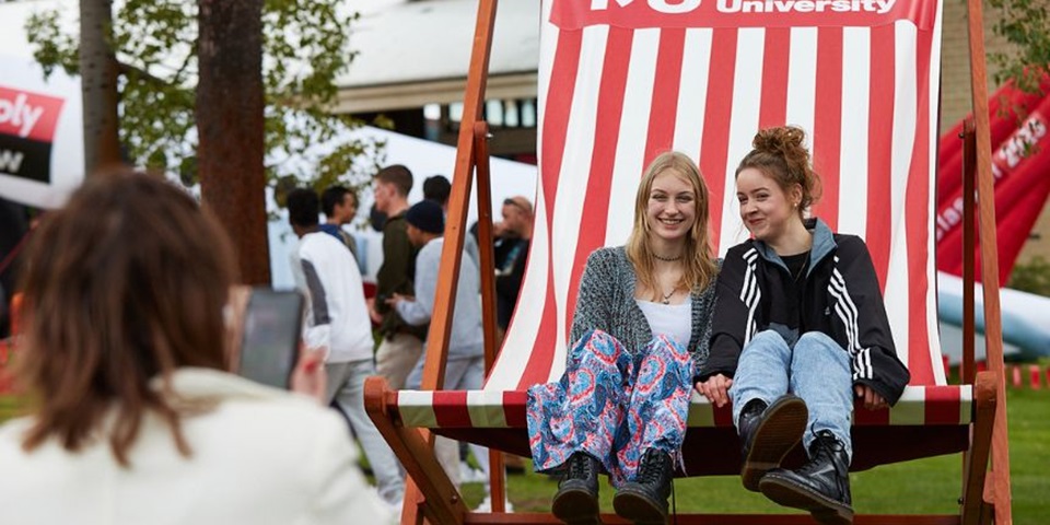 Two people sitting on a giant lawn chair smiling and laughing