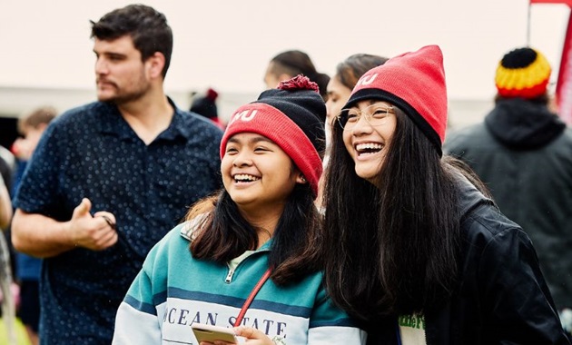 Two students wearing Murdoch Uni beanies smiling off camera