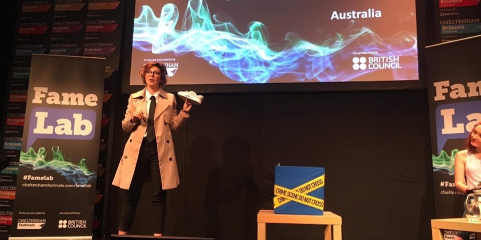 Paola Magni holding a shoe performing at the International FameLab finals 2019