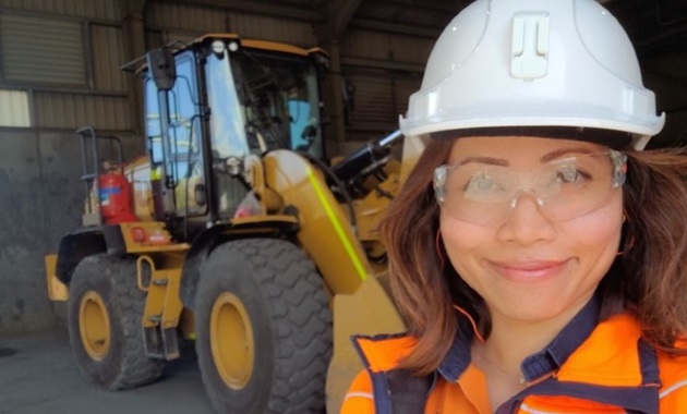 Pauline standing in hi-vis in front of a digger