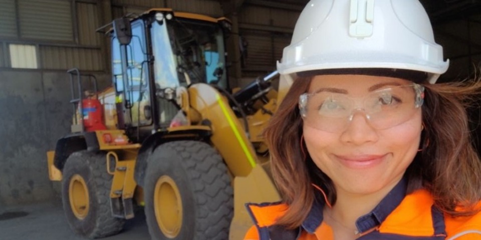 Pauline standing in hi-vis in front of a digger