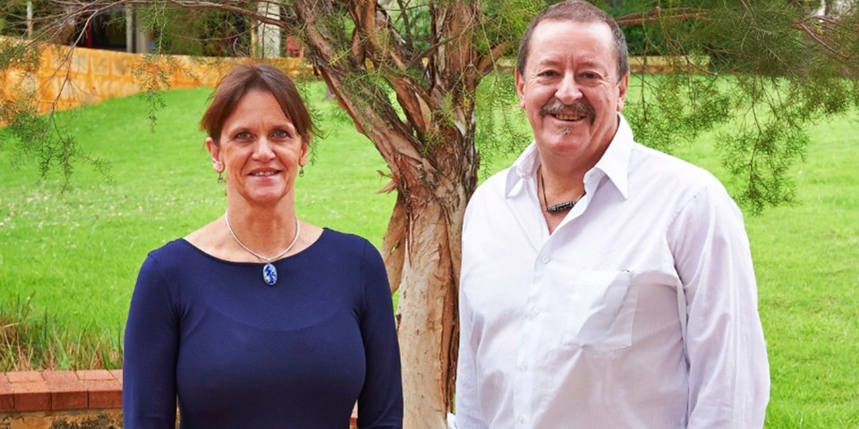 Professor Sue Fletcher and Professor Steve Wilton under a tree smiling at camera