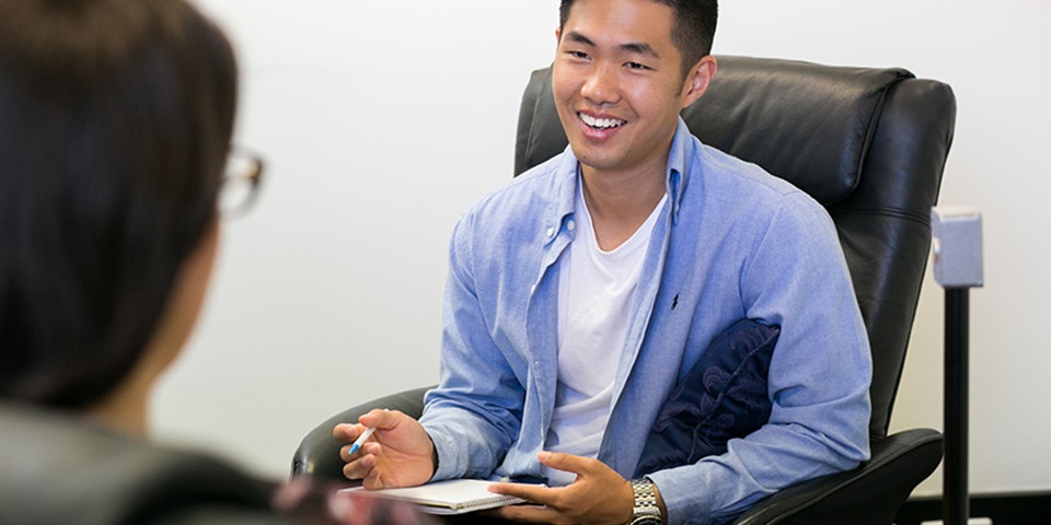 Male student in a therapy session, smiling.