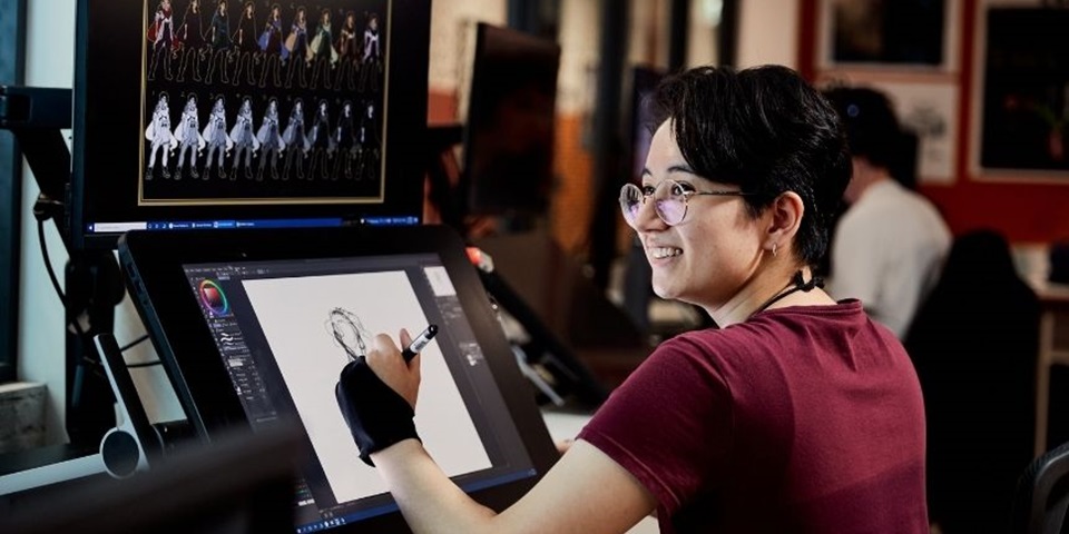 Student smiles and designs character on computer screen