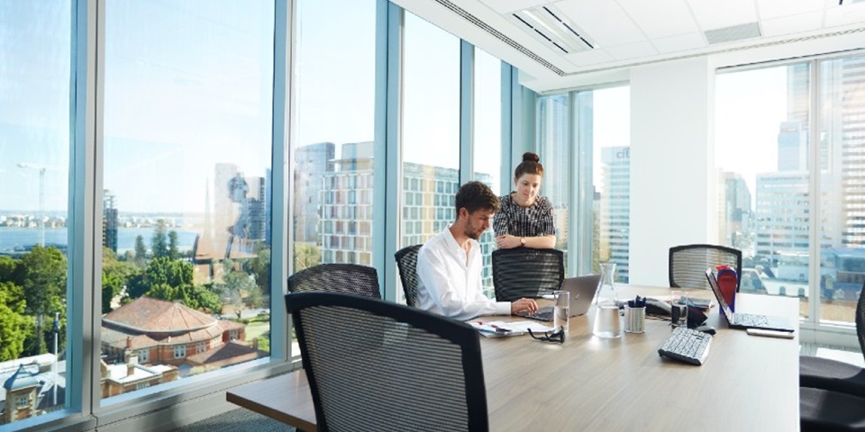 Two people working in a office building overlooking the city